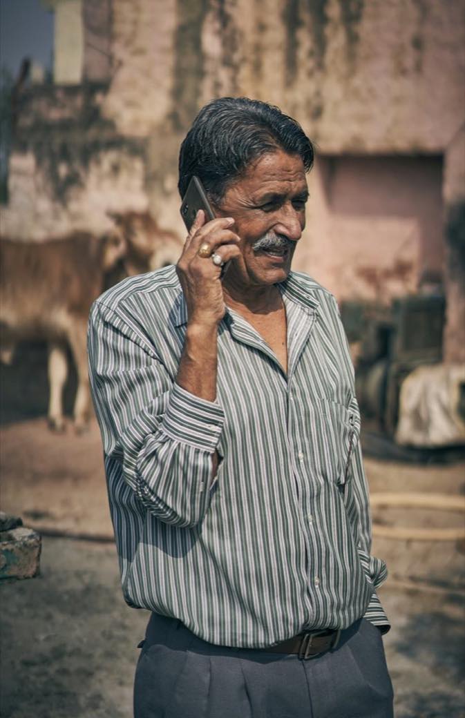 Farmer checking a phone in the field with cattle behind